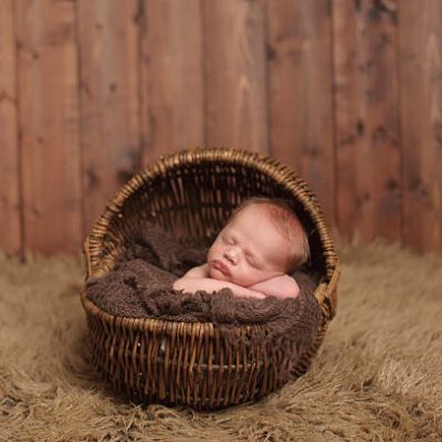 A newborn baby sleeping peacefully in a wicker basket.